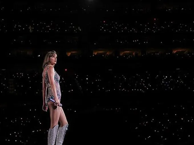 Foto de Taylor Swift sobre el escenario con el público de masas de fondo.