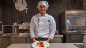Bryan Quinero posando a cámara en la cocina del CETT en su uniforme de cocina. 