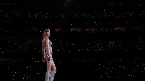 Foto de Taylor Swift sobre el escenario con el público de masas de fondo.