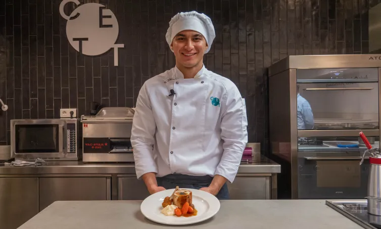 Bryan Quinero posando a cámara en la cocina del CETT en su uniforme de cocina. 