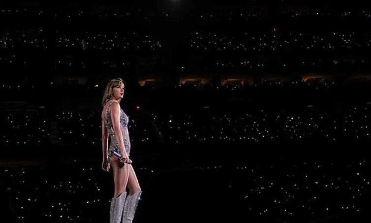 Foto de Taylor Swift sobre el escenario con el público de masas de fondo.
