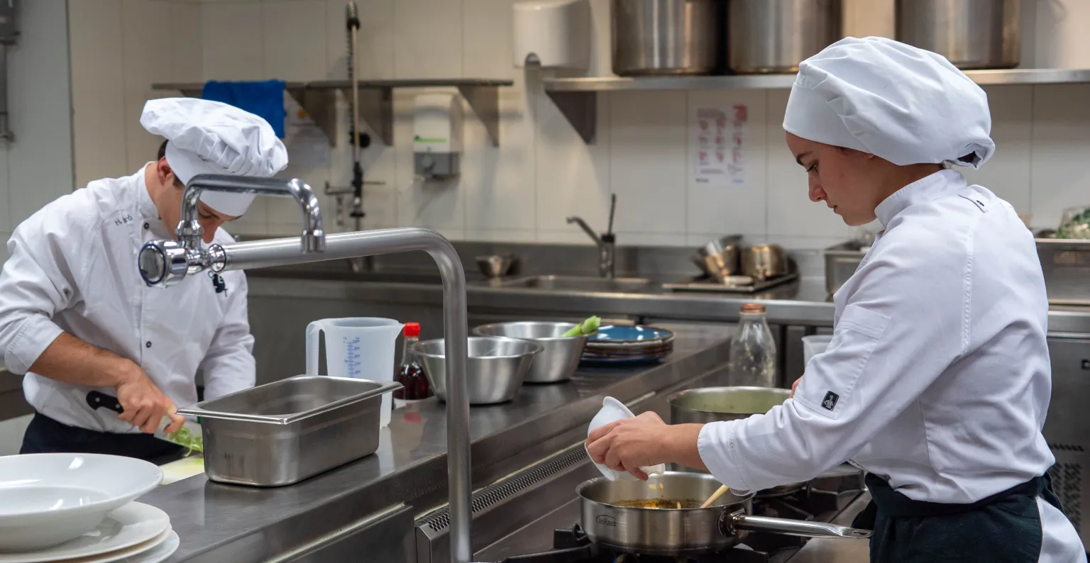 Alumnos preparando sus platos en la cocina.