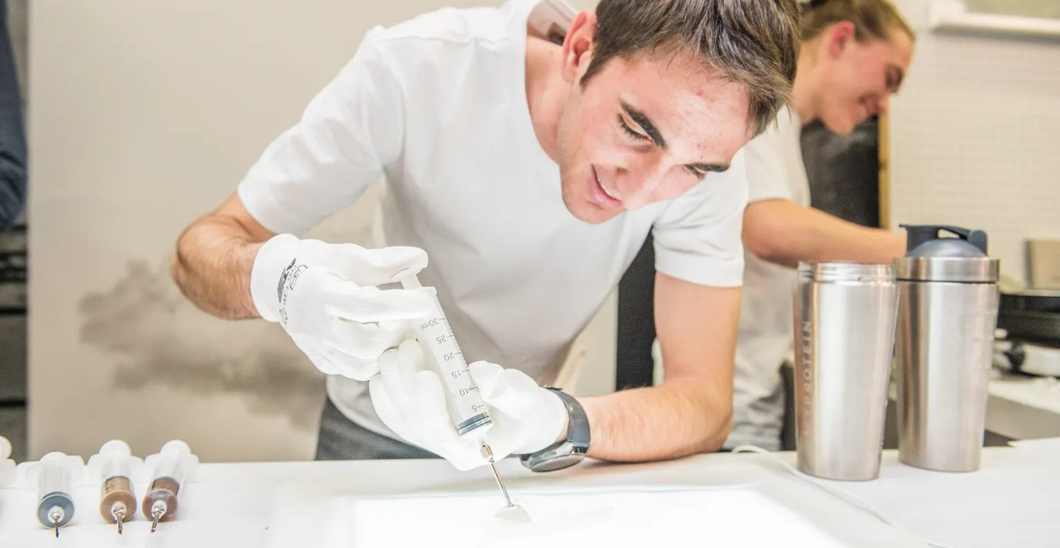 Alumno trabajando un alimento con una jeringuilla.