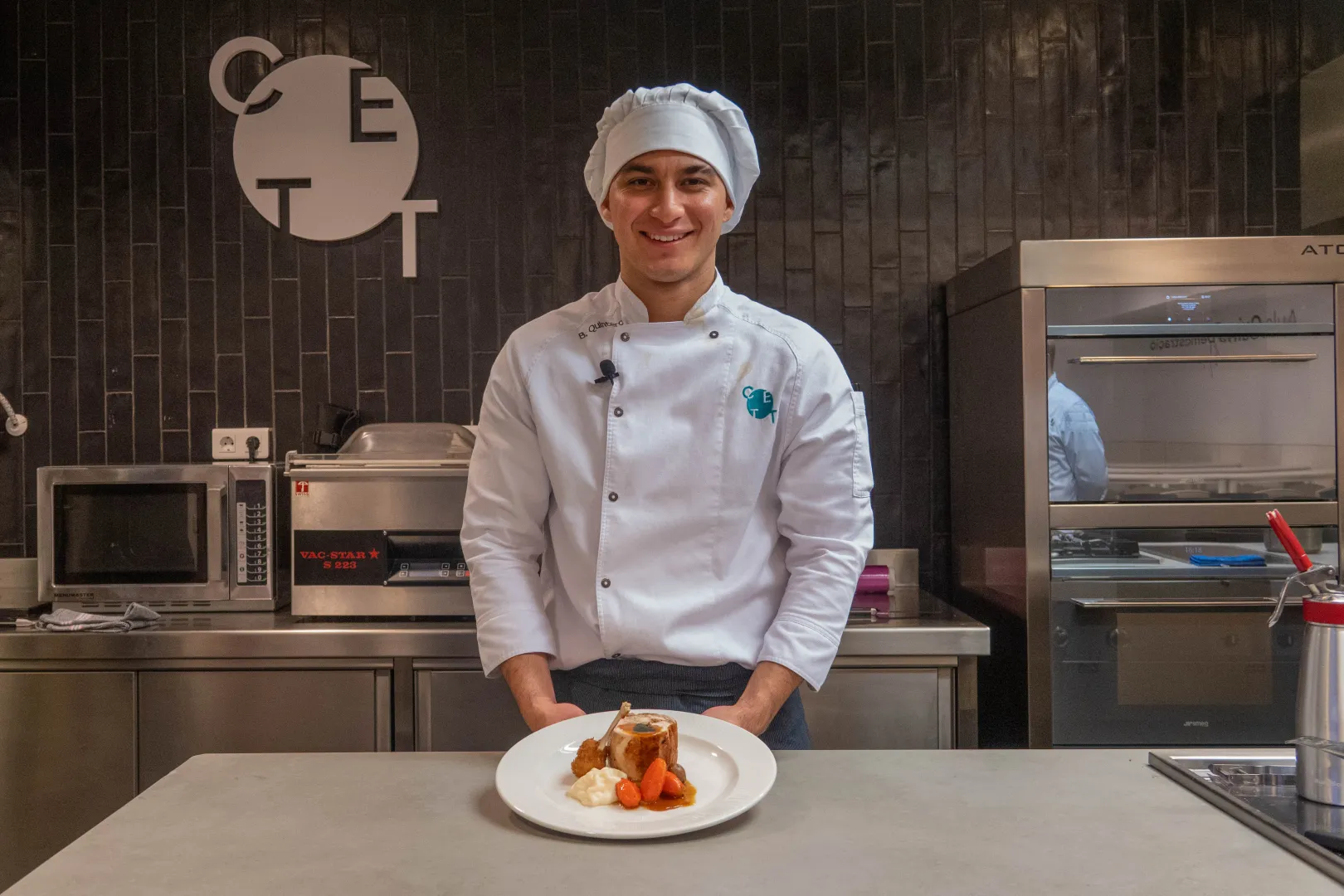 Bryan Quinero posando a cámara en la cocina del CETT en su uniforme de cocina.