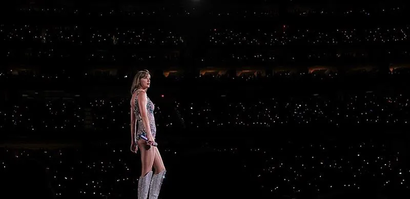 Foto de Taylor Swift sobre el escenario con el público de masas de fondo.